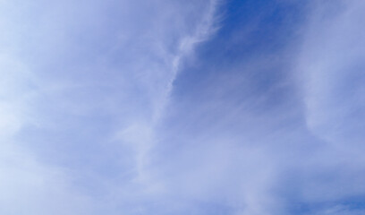 Fototapeta premium Blue sky with soft, wispy clouds spreading across the horizon, creating a peaceful and airy atmosphere. Ideal for background designs, nature themes, and outdoor-related projects.