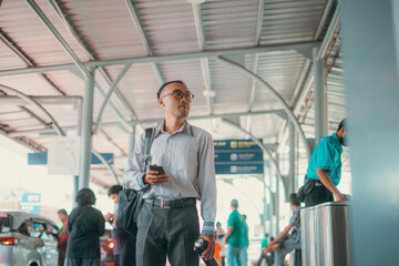 A businessman is using a smartphone while skillfully navigating the busy airport