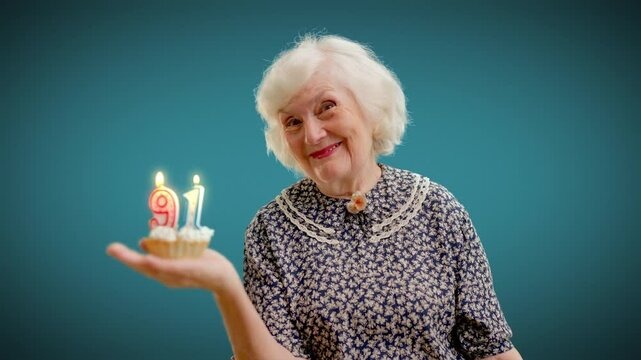 Portrait of happy grandma celebrating 91-th birthday, holding cake with candles