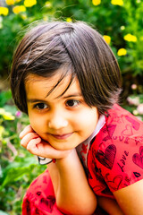 little girl in summer garden posing among flowers