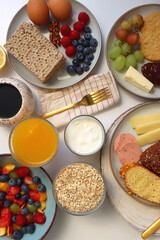 Assortment of various breakfast foods and drinks on the white table. Flat lay.
