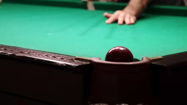 Russian billiards on a green table. A player hits a red ball with a cue and successfully pockets white into the corner pocket. A successful shot. Pastime at home playing sport game hobby. 4K footage