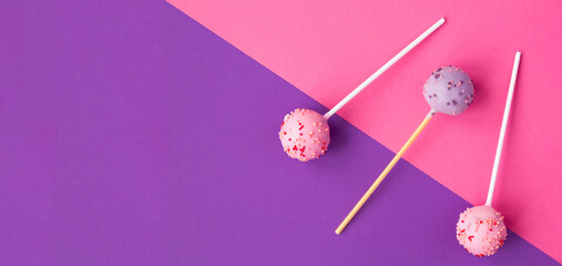 Cake pops with pink and purple glaze on the colored background. Top view. Copy space.