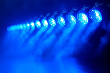 Bright blue stage lights illuminate smoke-filled dance floor at an energetic nightlife event, copy space for text, music advertising, nightclub advertisement