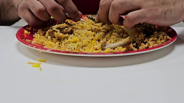 video of a person eating biryani. The biryani is on a large plate and is being consumed with spoon