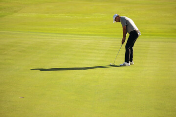 Golfer putting on a lush green golf course at a resort on a sunny day