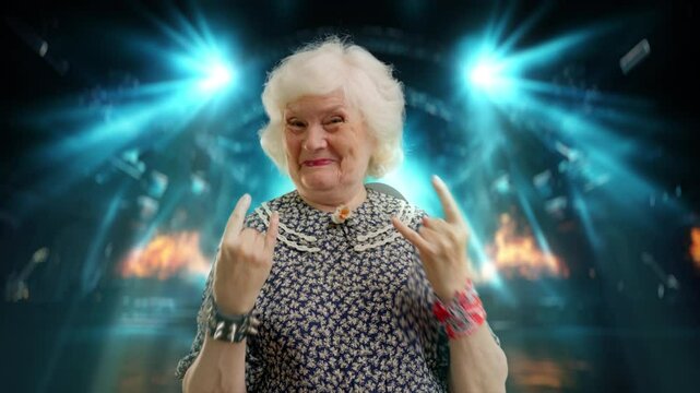 Contemporary grandma gesturing devil horns with hands on concert hall background