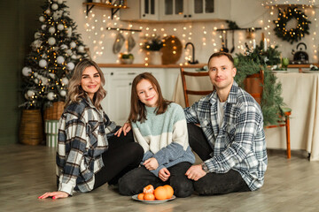 mom, dad and daughter are preparing for Christmas. decorate the Christmas tree in the kitchen of their home. christmas family holiday