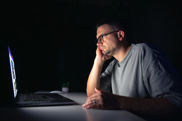 Young man works at the computer at night.