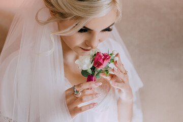 Naklejka premium A bride is lying on a bed with her hands on her face. She is wearing a white gown and a veil