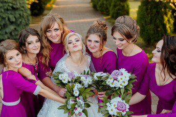 A bride is standing in front of a white archway with flowers and a white curtain. She is wearing a...