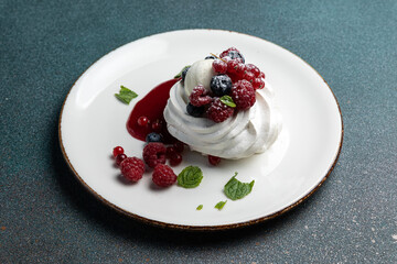 Pavlova with berries and whipped cream on a white plate