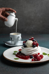 Pavlova with berries and whipped cream on a white plate