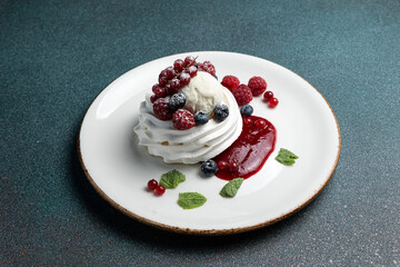 Pavlova with berries and whipped cream on a white plate