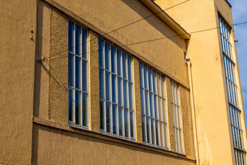 A building with a lot of windows and a yellow exterior. The windows are large and rectangular, and the building appears to be a commercial or office building