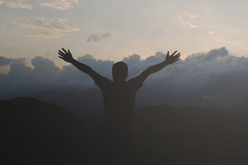 silhouette man is feeling happy and relaxed amidst nature and mountains in the morning.