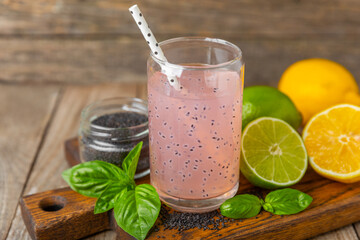 Diet detox cocktail with basil and chia seeds in a glass jar and a glass on a textured background....