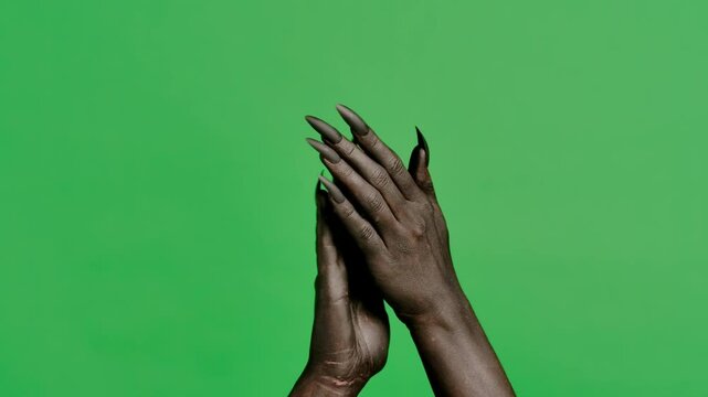 Creepy halloween devil monster hand in black paint with black nails clapping hands, applause isolated on chroma key green screen background, workspace mockup.