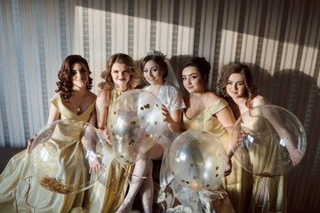 A group of five women are posing for a photo with balloons. The balloons are gold and white, and...