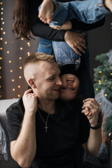 Caucasian father and young girl enjoying playful bonding time at home. Father expresses joy as daughter hangs upside down, showcasing closeness and fun.