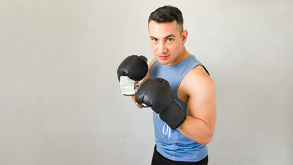 Hispanic male boxer, wearing boxing gloves, practicing his moves during a training session in the gym