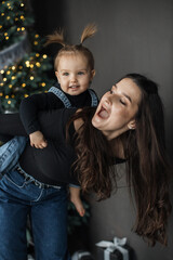 Caucasian mother and daughter celebrating festive season with joy. Young woman giving piggyback...