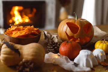 Happy Halloween! Carving Jack o lantern pumpkin, glowing ghosts and spiders on table in living...