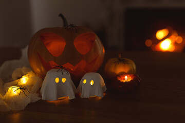 Happy Halloween! Glowing Jack o lantern and glowing ghosts with spiders in dark. Spooky atmospheric halloween decorations, space for text.