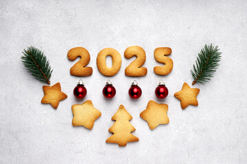 Cookies in the form of numbers 2025 in the center on the concrete background decorated with pine...