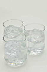 Three glasses of water with ice cubes, close up, isolated on white background