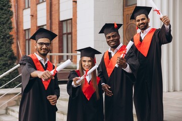 Group of Happy Graduates in Caps and Gowns Celebrating Graduation Day Outdoors