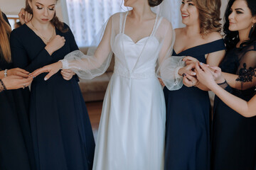 A bride and her bridesmaids are gathered together, with the bride wearing a white dress