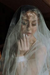 A woman is wearing a veil and is looking at the camera. The veil is made of a net-like material and...