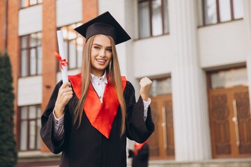 Cheerful Graduate Celebrating with Diploma in Hand Outside University Building