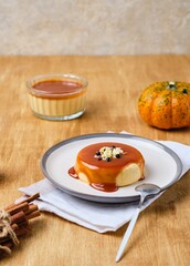 Dessert, creamy pumpkin panna cotta with caramel sauce on white plate on wooden background. Desserts without baking. Pumpkin recipes. Thanksgiving Day.