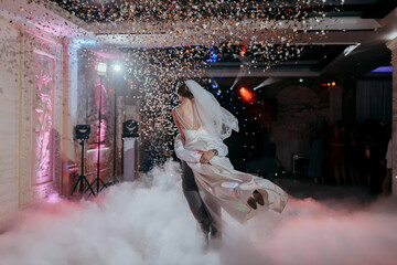 A bride and groom are dancing in the air with confetti falling around them. Scene is joyful and celebratory