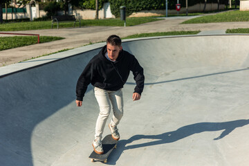 Skater energetically skating in the bowl at the skate park on a sunny day