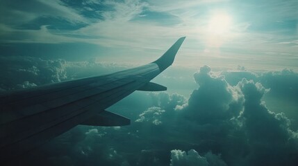 Obraz premium Aerial view from an airplane wing above clouds with sunlight filtering through.