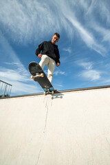 vertical Fish-eye view of a focused skater on the edge of the half pipe