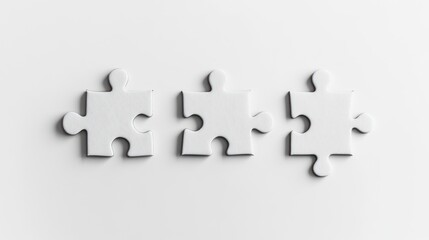 Obraz premium Three white puzzle pieces on a clean surface, symbolizing connection and problem-solving.