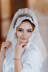 Fototapeta premium A woman wearing a white veil with lace and a red bracelet. She is smiling and looking at the camera