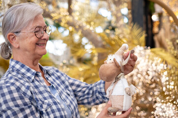 Smiling elderly woman shopping for Christmas selecting festive decorations in traditional shop