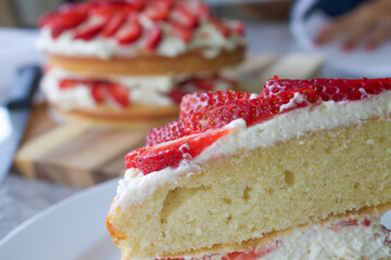 Variation of victoria sponge cake made with fresh strawberries and freshly whipped cream. Main cake on the background