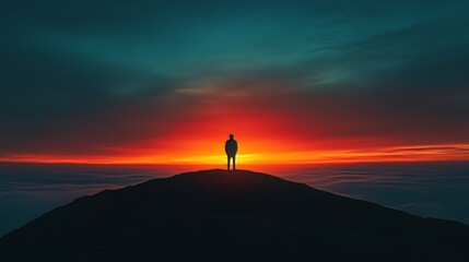 Fototapeta premium A man stands on a mountain top at sunset