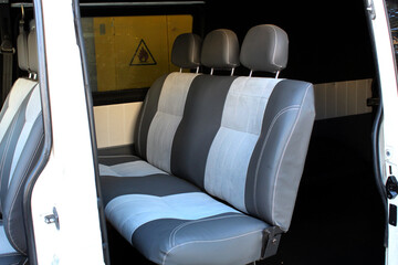 Second row of rear passenger seats in old passenger van. Grey leather rear passenger seats in minivan. Modern van interior. Vans rear seats row close up.