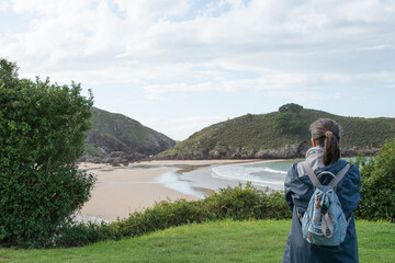 Fototapeta premium Unrecognizable woman looking to Barro beach with no people, in Llanes, Asturias