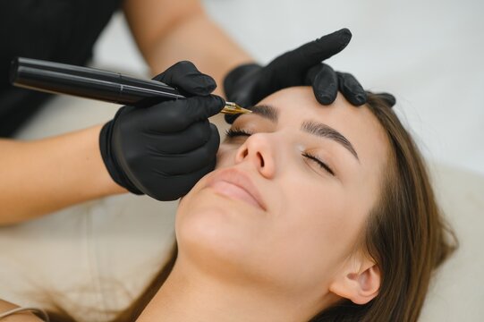 A cosmetologist applies permanent makeup to the eyebrows, eyebrow tattoo. eyebrow perm