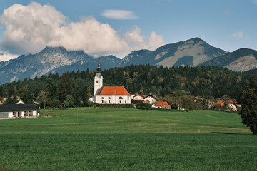 A picturesque church nestled in a tranquil valley surrounded by lush green fields and towering mountains. The idyllic scenery evokes a sense of peace and serenity. Slovenia