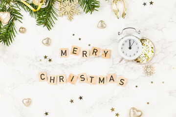 Top view background: Christmas tree branches and an inscription Merry Christmas from wooden blocks on white marble decorated for x-mas. New Year or Christmas Greating card. Clock indicating 00:00