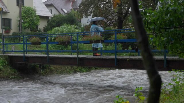 Stranger standing on bridge over strong current of river and making a photos